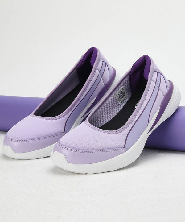 A side view of PUMA slip-on shoes for women, showcasing their sleek design and PUMA logo. The shoes are positioned with a slight angle to highlight their easy, slip-on style, with a clean background to emphasize their modern, casual appeal.
